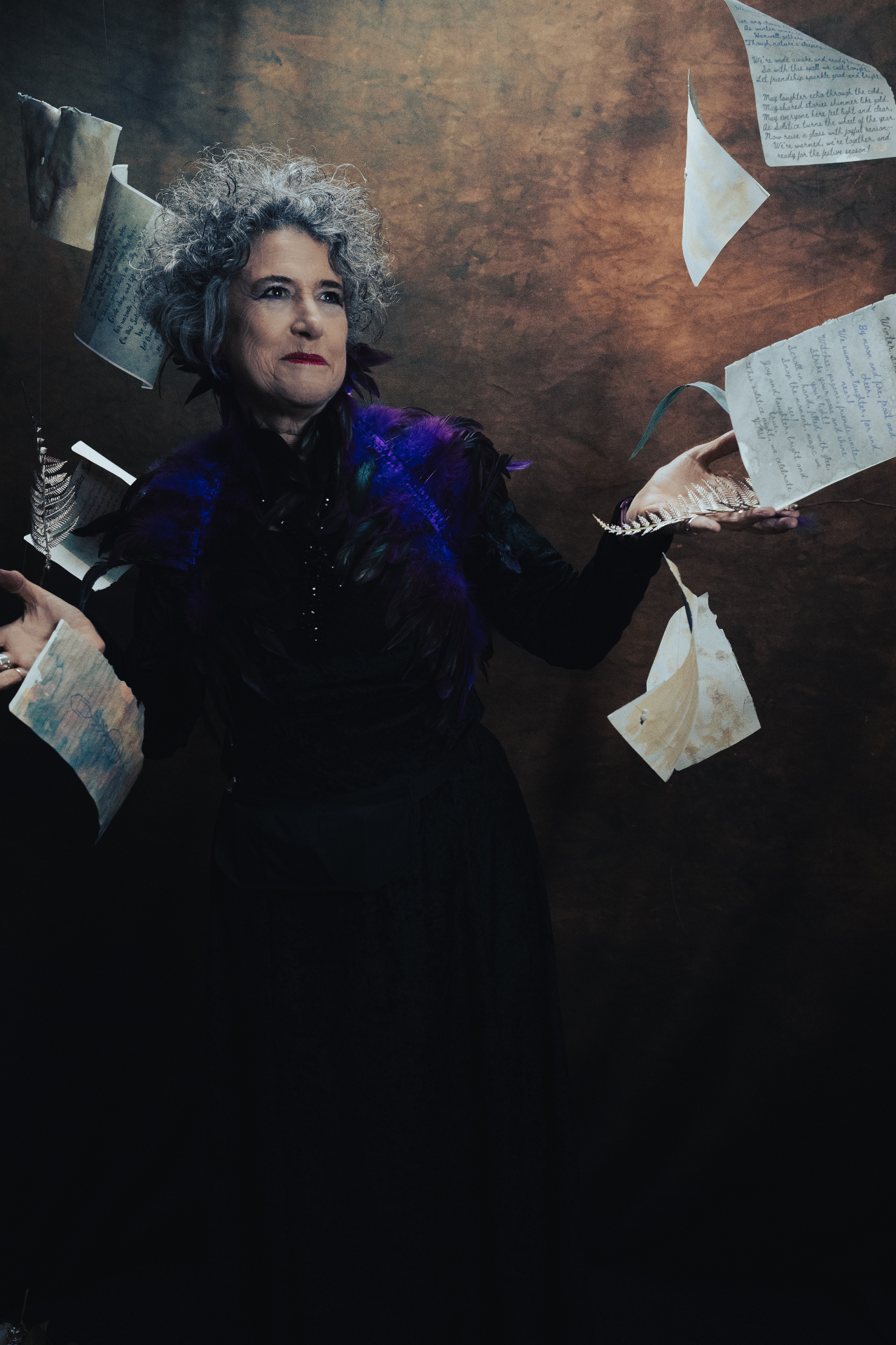 A portrait subject in dark costume holding a bowl and bottle.
